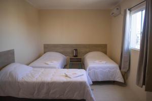 a room with two beds and a window at Hotel Marrocos in Pelotas