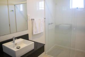 a white bathroom with a sink and a shower at Hotel Marrocos in Pelotas