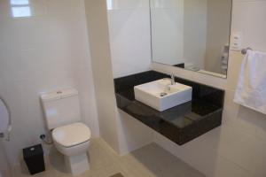 a bathroom with a white toilet and a sink at Hotel Marrocos in Pelotas