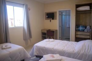 a hotel room with two beds and a window at Hotel Marrocos in Pelotas