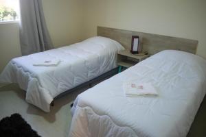 two beds in a hotel room with white sheets at Hotel Marrocos in Pelotas