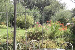 a garden through a fence with a table and flowers at Couleurs et jardin in Saint-Augustin