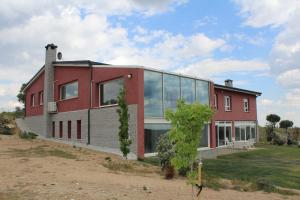 une maison rouge avec des fenêtres en verre sur un champ dans l'établissement Finca el enebro, à Valdemorillo