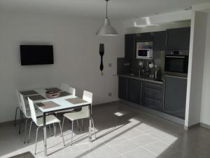 une cuisine avec une table et des chaises ainsi qu'une salle à manger dans l'établissement Les Portes de la baie, à Grand-Laviers