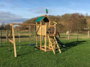 een houten speeltuin met een glijbaan en schommels bij Les Portes de la baie in Grand-Laviers