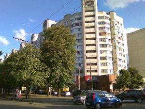 a blue car parked in front of a tall building at Apartment on Shevchenka in Cherkasy