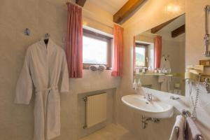 bagno con lavandino e accappatoio bianco di Hotel Weisses Lamm a Monguelfo