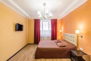 ブズルクにあるApartments on Moskovskaya 79のベッドルーム1室(ベッド1台付)、赤いカーテン付きの窓が備わります。