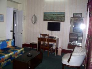 ein Wohnzimmer mit einem Sofa, einem Stuhl und einem TV in der Unterkunft Blue Chip in Kalkutta