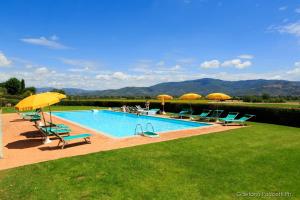 uma piscina com cadeiras e guarda-sóis em Casale Lombriciano em Cortona