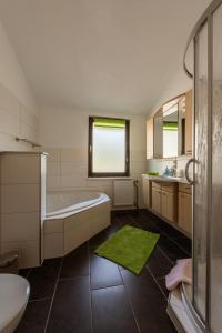 baño con bañera blanca y alfombra verde en Ferienhaus Little Rennsteig, en Eisenach