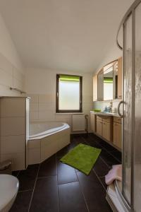 a bathroom with a white tub and a green rug at Ferienhaus Little Rennsteig in Eisenach