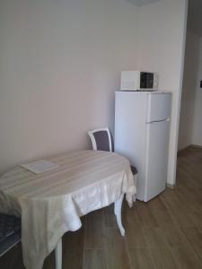 ブチャにあるПодобово апартаменти в м Бучаのテーブルと白い冷蔵庫が備わる小さな客室です。