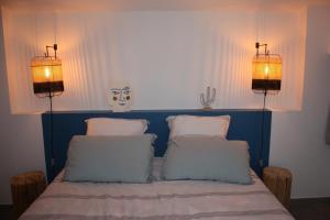 Una cama con tres almohadas y dos luces. en Le Tire Bouchon en Maraussan