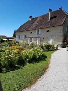 an old stone house with flowers in the yard at L'Aumônerie in Liesle