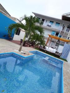 a blue swimming pool with a palm tree in front of a building at Apartamentos Isla Tropical in San Andrés