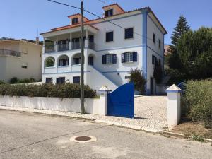 a white house with a blue gate in front of it at Casa Azul in São Martinho do Porto