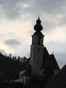 a church steeple with a cross on top of it at Anita's Zimmer in Engelhartszell