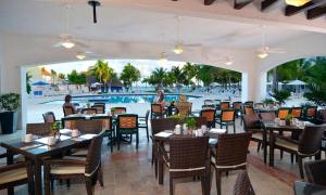 um restaurante com mesas e cadeiras e uma piscina em Cancun Beachfront Condo em Cancún