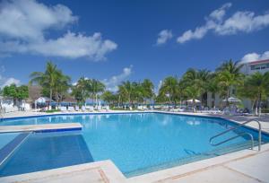 a large swimming pool with palm trees in a resort at Cancun Beachfront Condo in Cancún