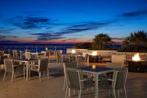 um pátio com mesas e cadeiras e o oceano à noite em Hard Rock Hotel Daytona Beach em Daytona Beach