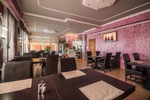 a restaurant with tables and chairs and a pink wall at Domin Osijek in Osijek