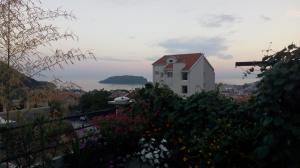 a white house with a red roof with flowers at Georgijevic Room & Apartments in Budva