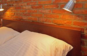 a bed against a brick wall with two lights on it at IRS ROYAL APARTMENTS Apartamenty IRS Morenowe Wzgórza in Gdańsk