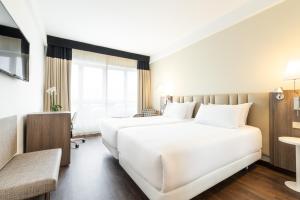 Habitación de hotel con 2 camas y escritorio en Eurostars Atlántico en A Coruña