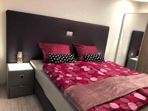 ein Schlafzimmer mit einem großen Bett mit rosa Bettwäsche und Kissen in der Unterkunft Am Weinberg in Senheim