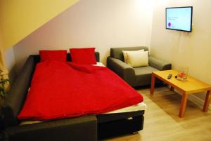 sypialnia z łóżkiem i kanapą z czerwonym kocem w obiekcie Bed & Breakfast Sielce Warszawa Chełmska w Warszawie