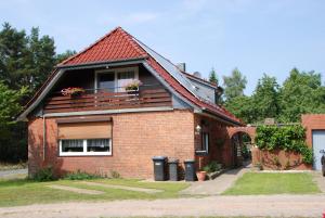 ein Backsteinhaus mit einem Balkon mit Blumen darauf in der Unterkunft Ferienwohnung-Bullendorf in Bullendorf
