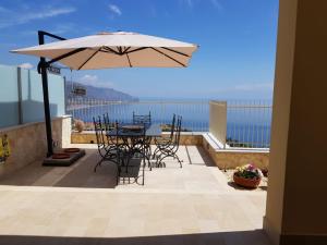 a patio with a table and chairs and an umbrella at Le Villette - Taormina in Taormina