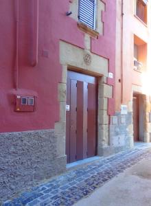 a red building with a red door on a street at Ca La Tambona in Sant Feliu de Pallerols