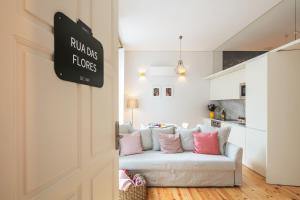 ein weißes Wohnzimmer mit einem weißen Sofa und rosa Kissen in der Unterkunft Indulge Porto Flats in Porto