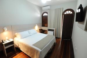 a bedroom with a bed and a desk and a window at POUSADA MILÊNIO LTDA in Ponte Nova