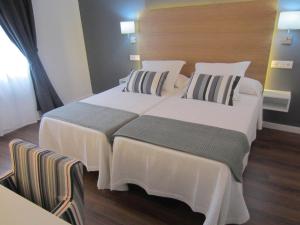 a bedroom with two beds with white sheets and pillows at Hotel Llorca in Platja de l’Almadrava