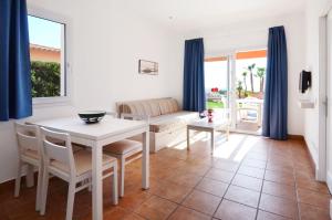 een woonkamer met een tafel en stoelen en een bank bij Apartamentos Mar Blau in Son Bou