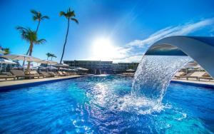 a pool with a fountain in a resort with palm trees at Royalton Bavaro, An Autograph Collection All-Inclusive Resort & Casino in Punta Cana