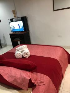 Apartaestudio en Chia في شيا: غرفة نوم بسرير احمر مع مناشف وتلفزيون
