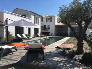 a pool with chairs and an umbrella next to a house at L'Île de Lumière in Rivedoux-Plage
