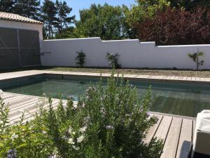 a swimming pool in a backyard with a white fence at L'Île de Lumière in Rivedoux-Plage