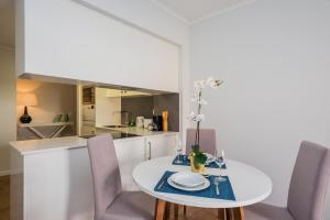 a white kitchen with a white table and chairs at 137 LuxResidence in Lisbon