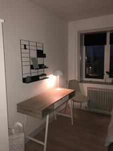 a desk with a lamp and a chair in a room at Hel lejlighed Thisted Midtby in Thisted