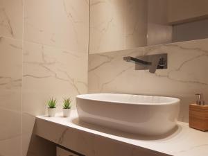 a white sink in a bathroom with marble walls at Milano Navigli Apartment - Via Savona in Milan