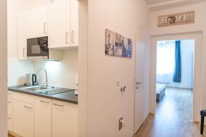 Minihotel Graz Apartments في غراتس: مطبخ مع دواليب بيضاء ومغسلة
