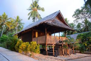 a resort building with a thatched roof and palm trees at Sunari Beach Resort 2 in Padang