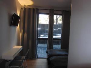 a living room with a window with a couch and a television at H La Cabaña in Pozuelo de Alarcón