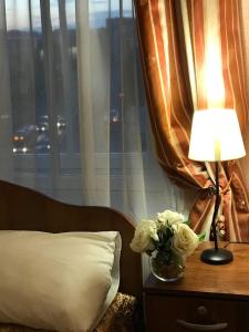 um quarto com uma cama com um candeeiro e um vaso de flores em Гостевые комнаты у Петропавловской em São Petersburgo