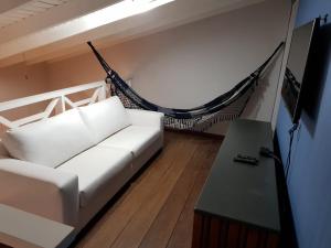 a living room with a white couch and a hammock at Lindo Flat em Maresias, 100m da Praia in Maresias